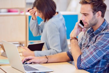 Arka planda çalışan kadın ile telefonda konuşan adam