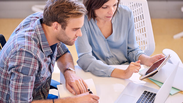 businessman and businesswoman looking at laptop screen while working together