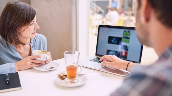 Tight shot of woman looking at laptop over mans shoulder — Stock Photo, Image