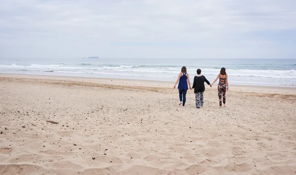 Três mulheres andando em uma praia longe da câmera — Fotografia de Stock
