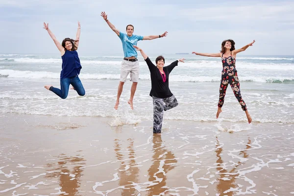 Famiglia felice saltando insieme sulla spiaggia nel paesaggio — Foto Stock