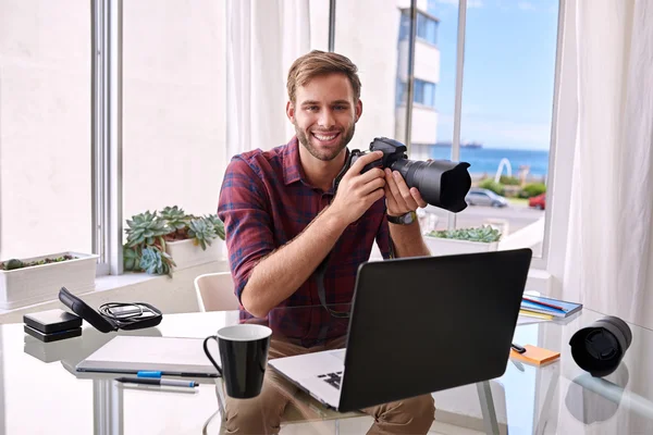 Jonge professionele fotograaf glimlachen op camera met een camera in zijn hand — Stockfoto
