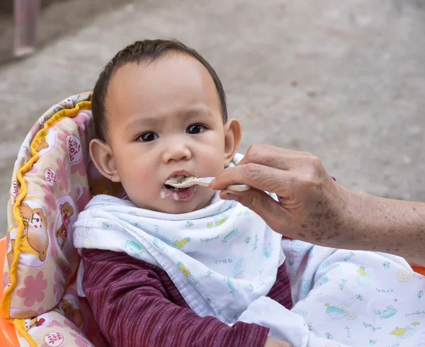 Baby eating food by spoon — Stock Photo, Image
