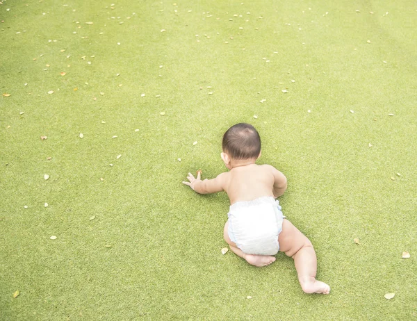 Adorable Asian baby boy crawling on the green grass field when h — Stock Photo, Image