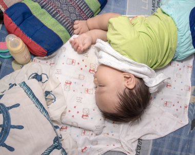 Yatakta, milyon tutan sağ elini uyuyan erkek Asya bebek