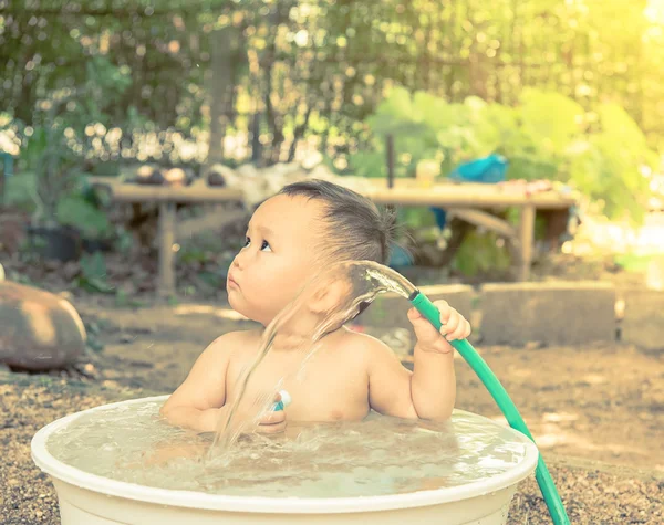 Bebê tomando banho fora da porta, mão do bebê segurando a mangueira que água f — Fotografia de Stock