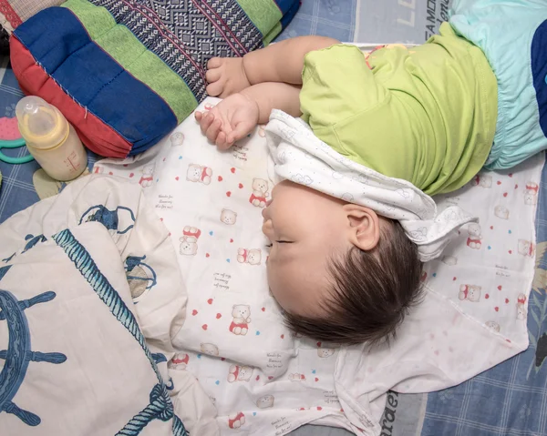 Yatakta, milyon tutan sağ elini uyuyan erkek Asya bebek