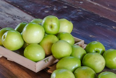 Ahşap masanın üstüne koy kutusunda yeşil maymun elma