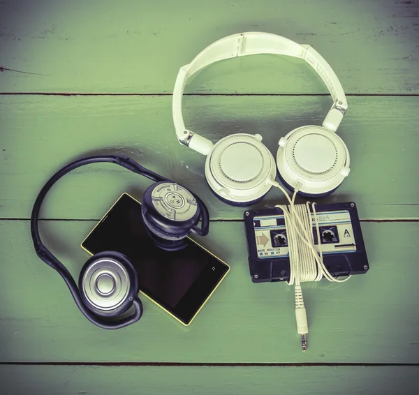 Cinta de cassette de teléfono inteligente y auriculares en el tablero de madera — Foto de Stock