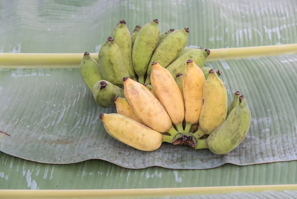 bunch of green and yellow color banana put on their leaf