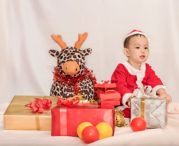 Dítě v červené Santa Clause s sobů panenka mezi — Stock fotografie