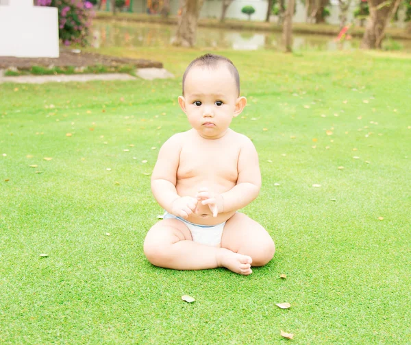 A little Thai baby sitting on the green grass field at the outdo — Stock Photo, Image