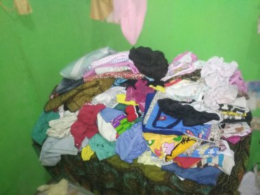 Giysiler üst üste yığılmış, düzgün düzenlenmemiş.