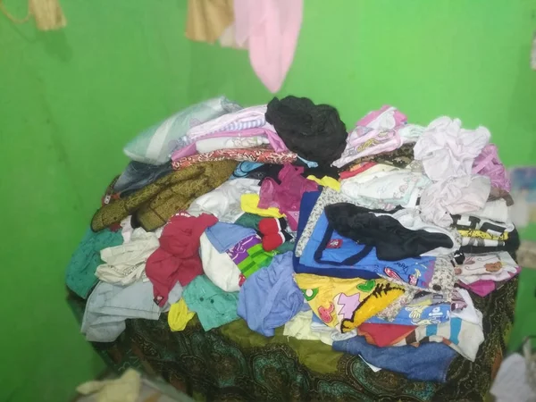 Giysiler üst üste yığılmış, düzgün düzenlenmemiş.