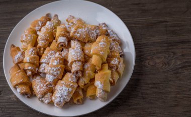 pudra şekerli süzme peynirler huş ağacının ahşap yuvarlak bir bölümünde beyaz bir tabağa uzanır.