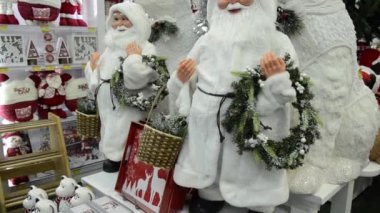 Noel Baba 'nın Noel süsleri, elinde Noel çelengi ve sepet taşıyan beyaz takım elbiseli haliyle. Ona kutup ayıları eşlik ediyor. Kamera hareketini yukarı kaldır.
