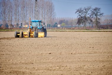 Bir tarım traktörü ilkbaharın başlarında yeni sürülmüş bir tarlada çalışır. Tarlayı yeni bir ekime hazırlıyor..