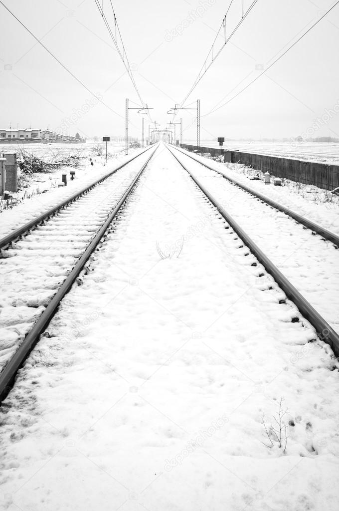 Railroad in the country, winter landscape with snow. Black and white photo