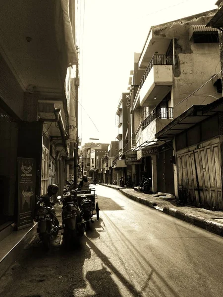 Surabaya, Endonezya - Ocak 2021: Endonezya 'nın Ampel, Surabaya, Endonezya' da park edilmiş motorsiklet motosikletli boş, sessiz dar bir dar sokakta monokrom fotoğrafçılığının eski antika klasik ortamı