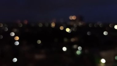 En üst kattaki çatıdan ya da havadaki bokeh arkaplanından görülen trafik ışıklarıyla gece şehir caddesinin bulanık görüntüsü