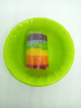 Beyaz arkaplanlı melamin tabakta gökkuşağı pastası