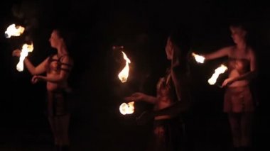 Ateş gösterisi gösterisi gösterisi. Ateşli kadın itfaiyeciler dans ederek siyah arka planda yanan meşaleleri yakıyor. Yavaş çekim