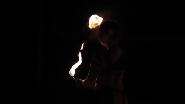 Actuación de espectáculo de fuego. Mujer intérprete de fuego mujer bailando con antorchas de fuego ardiendo sobre un fondo negro. Primer plano. Movimiento lento — Vídeo de stock