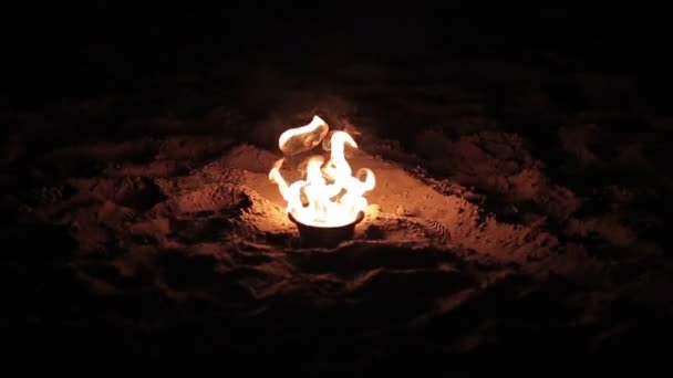 Пожежа горить у невеликій металевій пластині, що стоїть у піску на пляжі. крупним планом — стокове відео