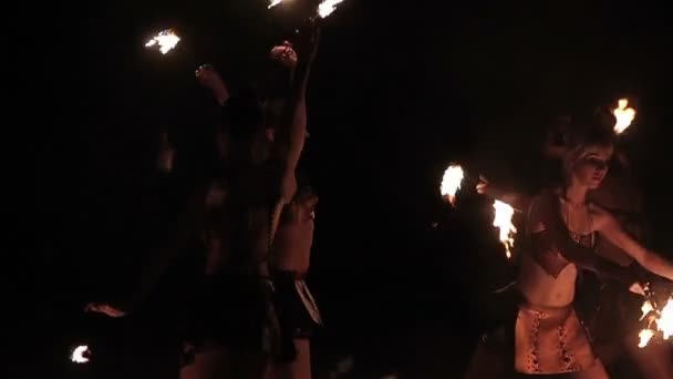 Fire show performance. Group of hot women female fire performers dance with burning fire torches on black background. Slow motion — Wideo stockowe