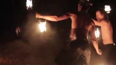 Ateş gösterisi performansını. Üç yakışıklı erkek ateşi performans dans iki yangın batons personel twirling her iki taraftan ateşledi. Ağır çekim