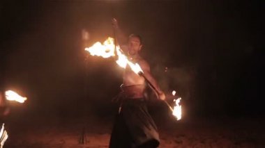 Ateş gösterisi performansını. Üç yakışıklı erkek yangın oyuncular iki yangın batons personel twirling her iki taraftan ateşledi. Ağır çekim