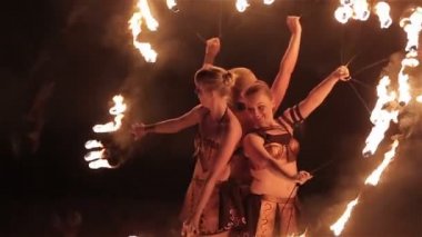 Ateş gösterisi performansını. Üç kızlar kadın ateş sanatçılar birlikte siyah arka plan üzerine hayranları olarak şeklinde yangın meşale yakma ile dans toplamak. Yakın çekim. Ağır çekim