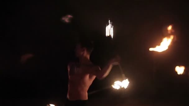 Spectacle de feu. Beau joueur de feu masculin tourbillonnant et jetant le bâton de feu personnel enflammé des deux côtés. Mouvement lent — Video