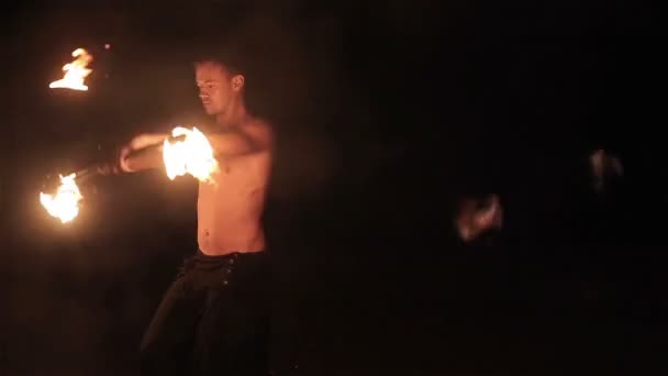 Spectacle de feu. Beau joueur de feu masculin tourbillonnant et jetant le bâton de feu personnel enflammé des deux côtés. Mouvement lent — Video