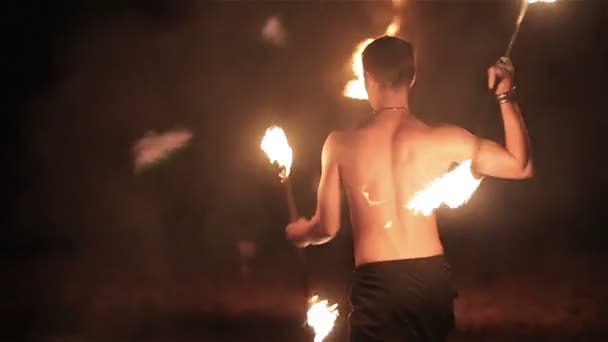 Desempenho de fogo. Bonito executante de fogo masculino girando e lançando fogo baton staff inflamado de ambos os lados. Movimento lento — Vídeo de Stock