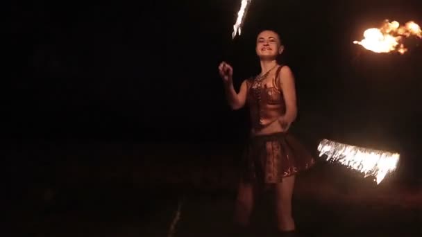 Пожежна вистава. Сексуальна жінка-виконавець вогню танцює крутяться вогняні змії навколо себе на чорному тлі. Крупним планом. Повільний рух — стокове відео