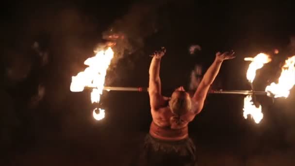 Fire show performance. Handsome male fire juggler performing contact manipulation with fire baton with several wicks dragon staff. Close-up. Slow motion — Stock Video