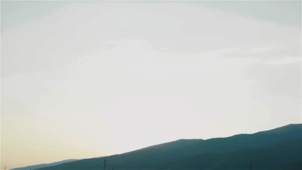 High voltage electricity tower pole and power lines at morning or evening in mountain range background. A lot of sky landscape. Pan — Stock Video