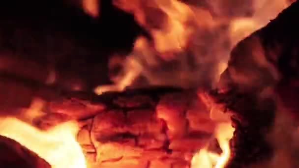 Macro primo piano di tronchi di legno caldo frizzante di fuoco ardente su sfondo nero scuro con spruzzi gialli e arancioni di fiamma — Video Stock