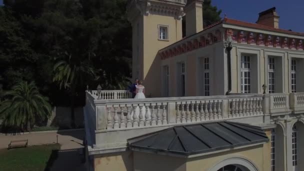 Love couple hold hands stand on balcony beautiful house. Royal family husband wife kiss on terrace of small beautiful chateau in Europe France Grasse mountain area. Wedding reception luxury lifestyle — Αρχείο Βίντεο