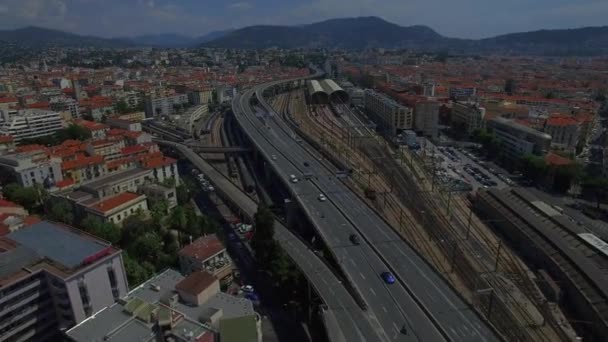 4K Niza ciudad carretera carretera tráfico Francia vista aérea desde arriba. Vuele sobre la autopista de múltiples carriles y la estación de tren en el paisaje urbano de Niza Europa con fondo de montaña. Ocupado gran ciudad concepto de vida — Vídeo de stock