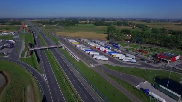 Fly over parking lot for truck lorries both sides of highway road with pedestrian overpass bridge above and gas filling station aerial top view 4K HD. Drivers working hours truck stop and rest area — Αρχείο Βίντεο
