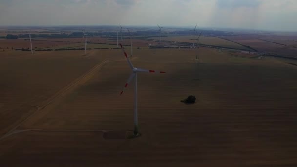 Vídeo aéreo da fazenda da turbina eólica 4K HD sobrevoa. Moinhos de vento geradores de energia renovável em campos rurais impacto do dióxido de carbono luz solar do céu divino apocalíptico escuro na Europa Alemanha — Vídeo de Stock