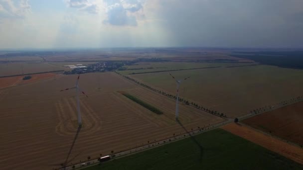 Moinhos de vento de turbina eólica 4K HD para produção de energia elétrica renovável em campos rurais e caminhões rodoviários locais movem antenas de cima. Futuro dos veículos automóveis eléctricos de transporte — Vídeo de Stock