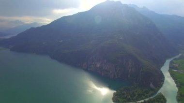 Nehir 4 k görünüm hava göle akıyor. Kayalık Alpler Dağı ve Como Gölü güneş Parlatıcı yansıma turkuaz su en iyi video içine akan nehir üzerinde uçmak. Lombardy İtalya ünlü turistik yerler