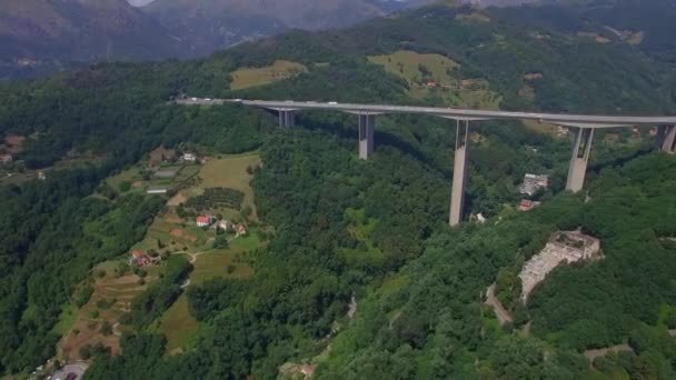 Highway bridge mountain viaduct road aerial 4k. Cars lorry truck traffic Europe cargo freight logistics. Vehicles move tunnel exit to massive bridge overpass above river or road top view in Italy Alps — Stockvideo