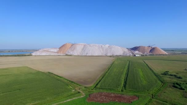 Pilhas de rejeitos deixadas após a extração de fertilizantes potassa de minas subterrâneas aéreas 4k. A produção de sal de potássio a partir de minério extraído implica resíduos líquidos derramados em bacias e armazenamentos sólidos em minas. — Vídeo de Stock