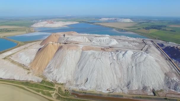 Tailings piles left after potash fertilizer extraction from underground mines aerial 4k. Potash salt production from extracted ore entail liquid waste poured into basins and solid stockpiling on mines — Stock video
