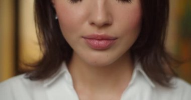 Kapalı alanda ağır çekimde sıcak çay içen kadın yüzünün detaylı makro görüntüsü. Elinde makyaj fincanı olan tanınmamış bir kadın yüzünü kapatmış. Dudaklar ruj yüz güzelliği kozmetiği.