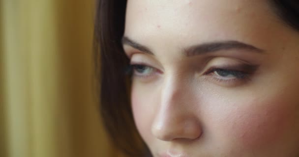 Gedetailleerde macro shot van vrouwelijk gezicht kijkend in de verte met droevige uitdrukking ondiepe handheld apparaat. Close-up portret van pensieve vrouw denken van het leven problemen slow motion. Huidverzorging cosmetica make-up — Stockvideo